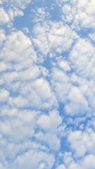 Obraz premium Scattered white clouds form a soft pattern across blue sky. Natural light creates even texture without strong contrast.