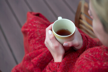 Young girl wrapped in plaid with cup of tea in hands