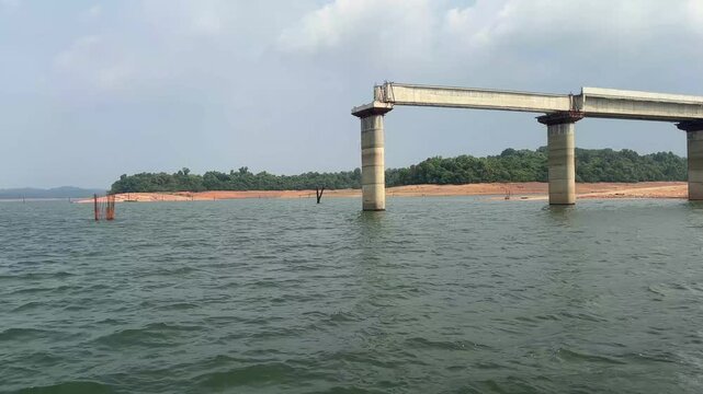 Concrete bridge structure under construction near riverbank. Real time during ferry trip