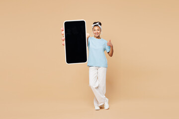 Full body young woman of African American ethnicity wear blue t-shirt casual clothes hold use blank...