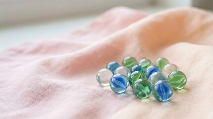 Colorful marbles arranged on a soft pink fabric.