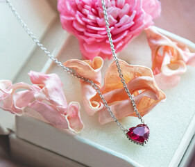 Jewelry. Metal chain (necklace) with stylish pink heart pendants in gift box. Rose and petals of rose creating, tender, romantic atmosphere. Valentine's day,  mother's, woman's day, love holidays.