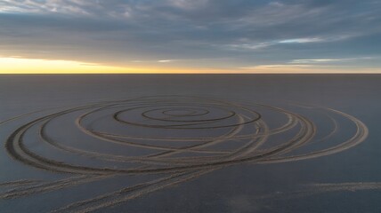 Naklejka premium Spiral pattern on sandy beach at sunset