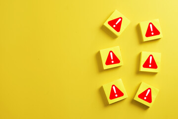 Group of yellow wooden blocks with red exclamation mark symbol arranged on right side with copy space on yellow background. Danger alert,risk management,error notification,emergency caution concept.