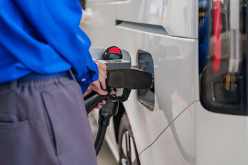 Close-up of a man&rsquo;s hand holding a fuel nozzle at a gas station.