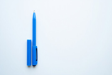 Minimalist composition with a bright blue pen and its cap placed separately on a clean white background viewed from above