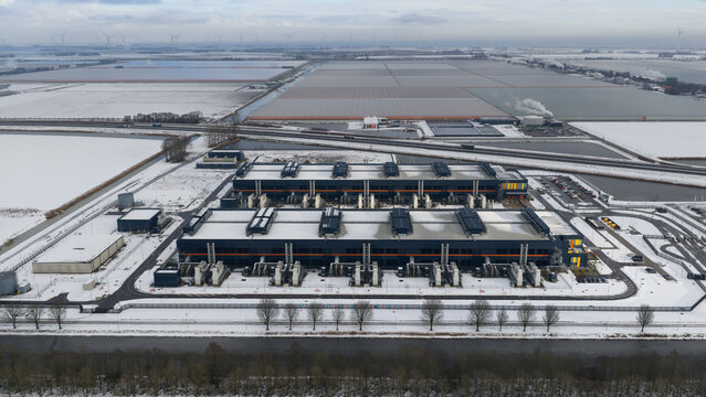 Aerial view of a stark, snow-dusted landscape, where the Agriport datacenters stand out with their dark, geometric forms against the flat, white expanse, Middenmeer, North Holland, Netherlands.