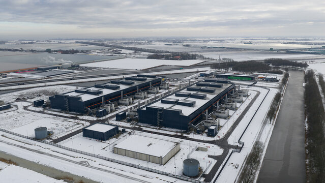 Aerial view of boxlike, dark-colored buildings stand in stark contrast to the snow-covered landscape, showcasing industrial architecture, Middenmeer, North Holland, Netherlands.