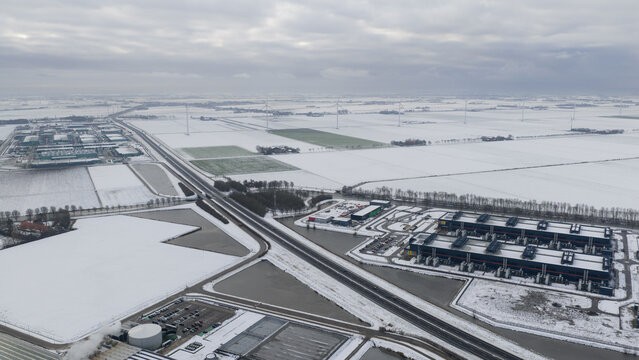 Aerial view of a winter landscape where snow dusts the fields and outlines the modern architecture of Agriport datacenters, Middenmeer, North Holland, Netherlands.