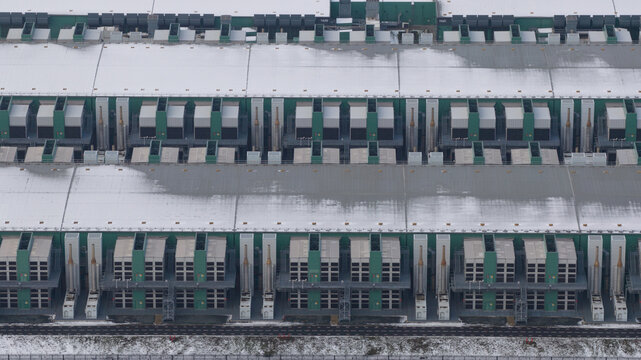 Aerial view of the Agriport datacenters, a tapestry of snow-dusted roofs and rhythmic green accents, a stark contrast against the muted winter landscape, Middenmeer, North Holland, Netherlands.