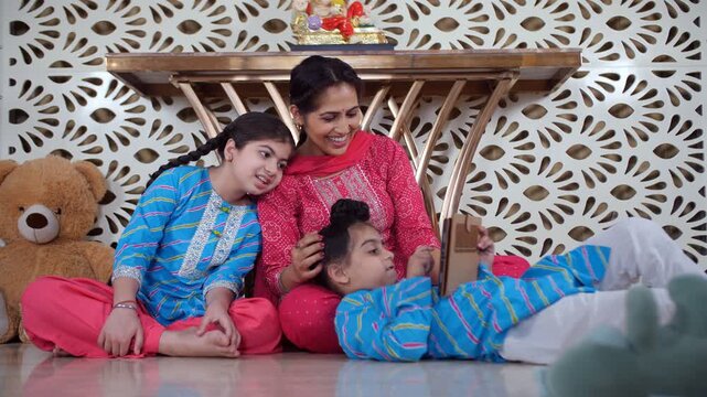 A happy Indian mother and her cute little kids - using a tablet  modern lifestyle  Punjabi family  nuclear family  single mother. A cheerful Indian lady and her young kids are watching a cartoon / ...