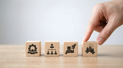 Hand interacting with wooden blocks displaying business concepts of teamwork organization collaboration and achievement on a wooden desk with bright l