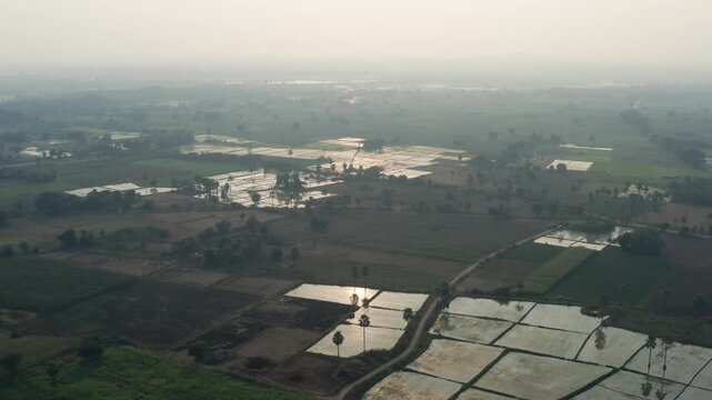 Aerial panorama of irrigated farmland with reflective water plots and patchwork fields near Warangal, showing rural agriculture, seasonal cultivation, and calm countryside.