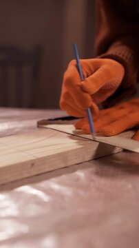 Close up of carpenter hands measuring wooden plank with ruler and pencil in workshop
