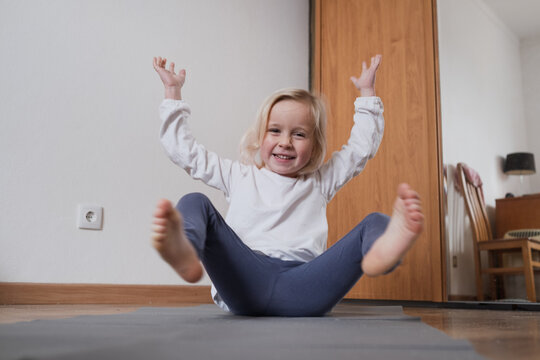 Little girl practicing yoga in Boat Pose Navasana on a mat.