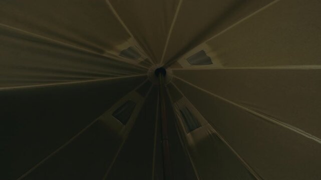 Dark Umbrella Interior Converging Ribs Overhead, Khaki Fabric Panels And Metal Spokes Surrounding Central Hub, Low Light Studio