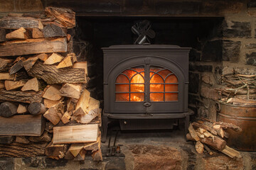 Cast Iron Wood Stove in a Stone Fireplace with  Stacks of Firewood