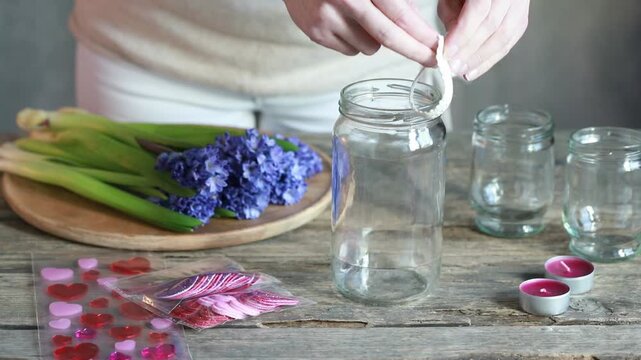 Florist at work: a woman shows how to make a charming vase and candle holders for Valentine's Day from ordinary jars. Step by step, tutorial. Images available.