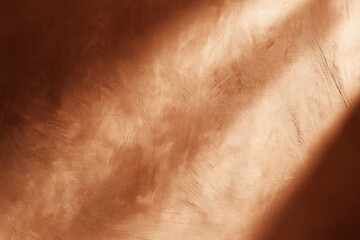 Naklejka premium Pumpkin-toned plaster wall background with soft natural imperfections, gentle side lighting creating depth and shadow, cozy autumn atmosphere without objects