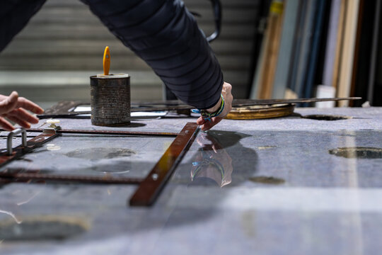 Miroitier professionnel rempla&ccedil;ant les verres d&rsquo;une tr&egrave;s vieille pendule au bois fortement ab&icirc;m&eacute;, mettant en valeur un travail de restauration artisanale sur un objet patrimonial.