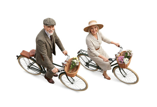 Elegant senior couple riding vintage bicycles with flowers in baskets on white background high angle view