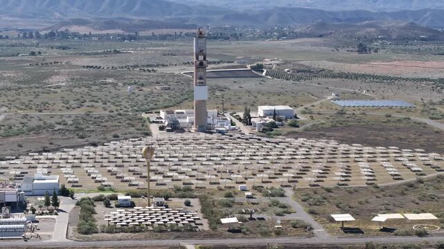 Drone aerial close view of solar tower with heliostat mirrors and service buildings at Plataforma Solar de Almeria Tabernas Desert Spain research site