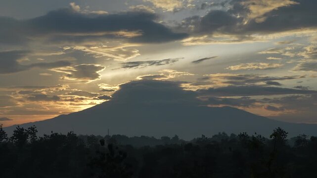 Majestic golden sunrise mountain timelapse with sun rays. Dramatic morning sky and moving clouds over Mount Ciremai, Indonesia.