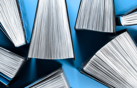 Thick books in half open state stand on blue background.
