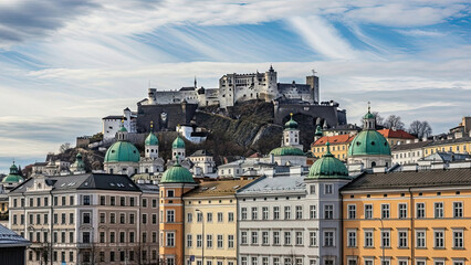 Historic cityscape with medieval fortress and colorful buildings viewed from a distance under a cloudy sky