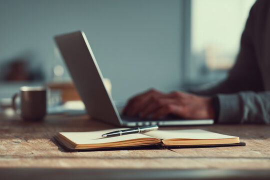 businessman working on his laptop, taking notes with a pen, closeup