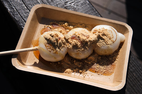 Sweet dango balls on a skewer, topped with kinako powder and syrup in a disposable tray