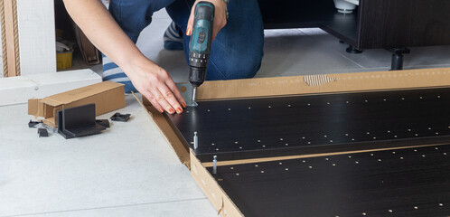 DIY furniture assembly process with cordless drill, flat pack cabinet installation at home, step by step home improvement work.