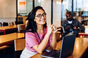 Smiling woman working on laptop in cafe