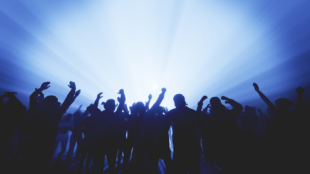 Energetic crowd at a music concert with hands raised towards the stage lights