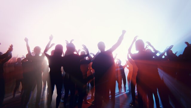 Enthusiastic crowd enjoying a concert with raised hands and bright stage lights