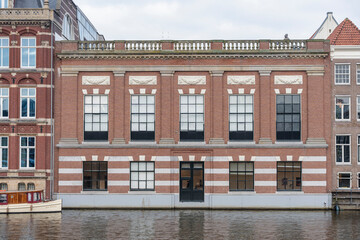 Obraz premium View of a brick building along a canal in Amsterdam, Netherlands.