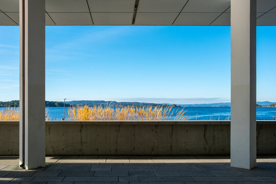 Modern urban architecture columns frame a minimal terrace by the sea and waterfront under clear sky offering open view and calm space