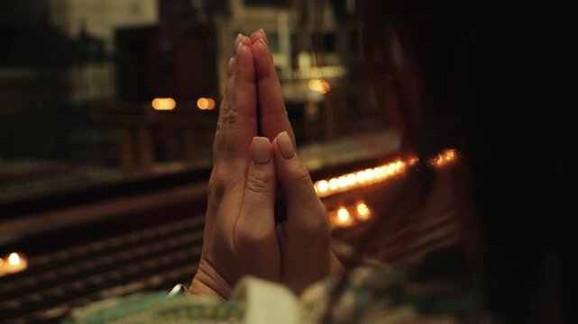 A woman praying near lit candles in a church.