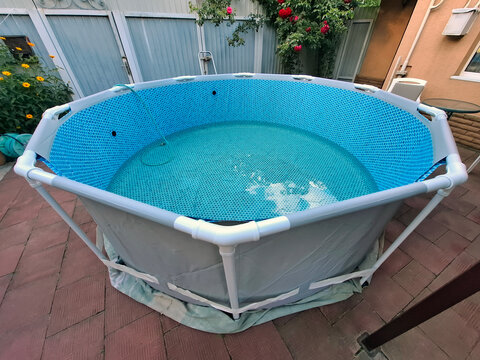 Outdoor man-made open-air swimming frame pool. Water is pouring into the pool