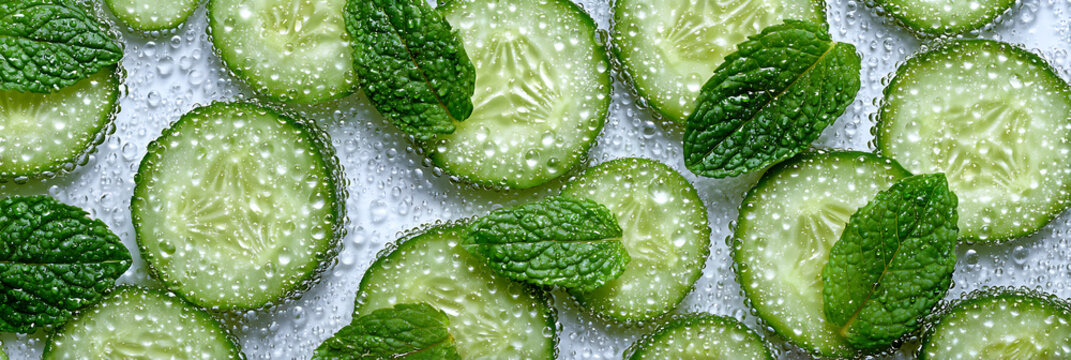 Crisp cucumber slices and fresh mint leaves in effervescent water, a vibrant composition symbolizing purity and hydration for beauty and health concepts.