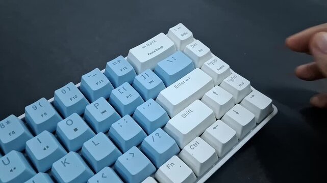 Finger pressing Enter Key on blue and white mechanical keyboard.