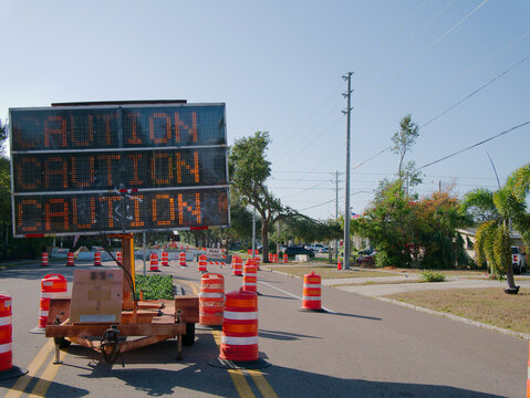 Road Closed Sign With Barricades And Traffic Cone In Construction Zone On City Street Intersection. Large road closed sign with striped barricades and an orange traffic cone, indicating construction w