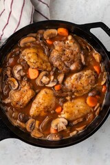 Classic Coq au Vin served in a modern gourmet style, featuring tender chicken simmered in red wine with herbs, presented in a clean, elegant composition for refined culinary visuals.