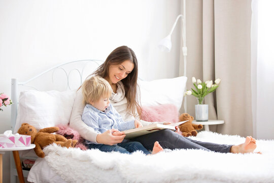 Mother and child, toddler boy, reading book in bed