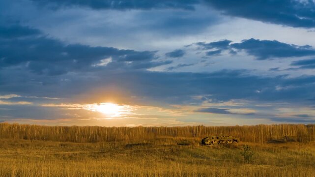 damaged armored personnel carrier stay among prairie at the sunset time lapse scene