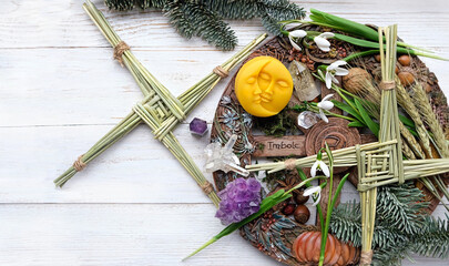 Wiccan altar for Imbolc sabbat. wheel of the year with Brigid's cross amulets, crystals, snowdrops flowers, moon talisman on wooden table. witchcraft, magic ritual for Imbolc holiday, spring equinox
