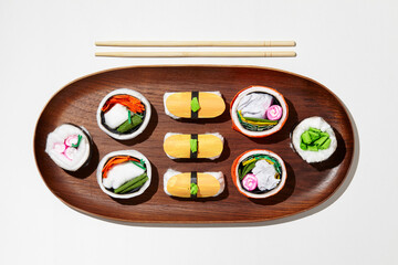 Set of paper sushi on a wooden plate over white background. Top view with copy space. Pure and fresh concept and composition.