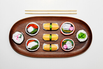 Set of paper sushi on a wooden plate over white background. Top view with copy space. Pure and fresh concept and composition.