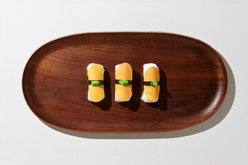 Set of paper sushi on a wooden plate over white background. Top view with copy space. Pure and fresh concept and composition.