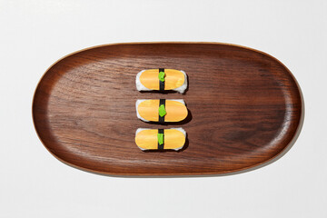 Set of paper sushi on a wooden plate over white background. Top view with copy space. Pure and fresh concept and composition.